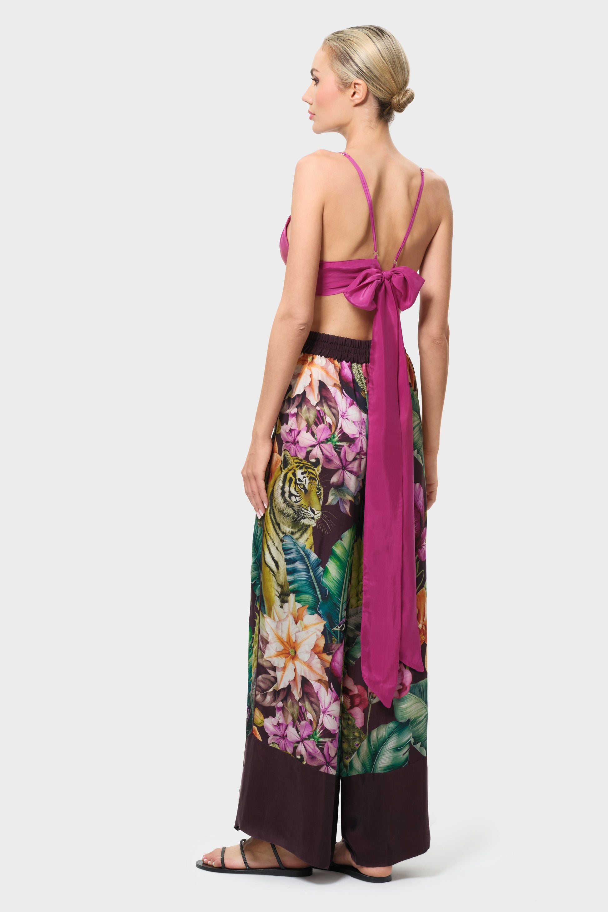 Woman wearing a pink top and colorful floral pants on a white background