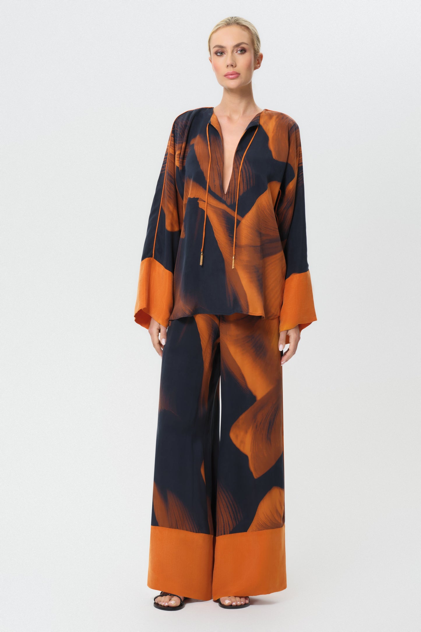 Woman wearing an orange patterned outfit on a white background