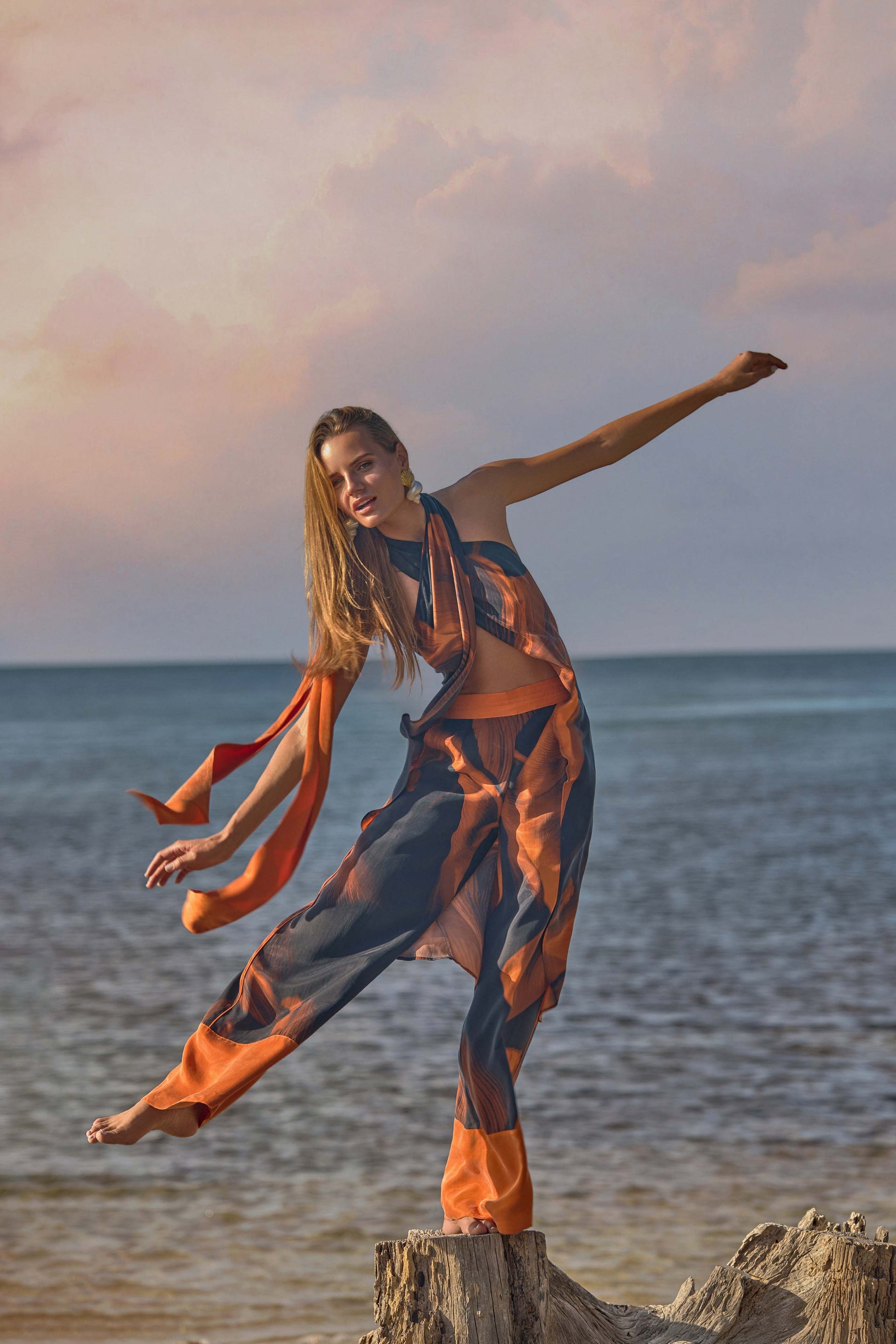 Woman in an orange and black outfit  by the ocean 