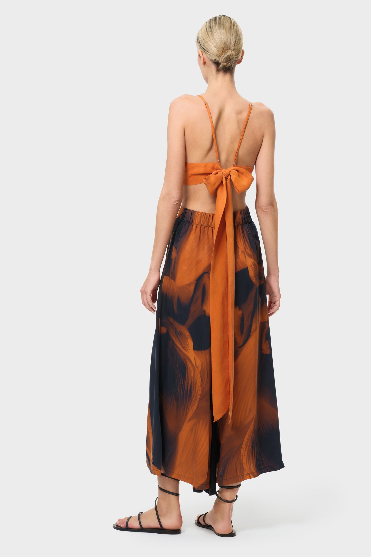 Woman wearing an orange top and patterned skirt on a white background