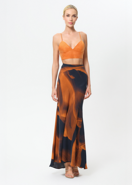 Woman wearing an orange top and black and orange patterned skirt on a white background