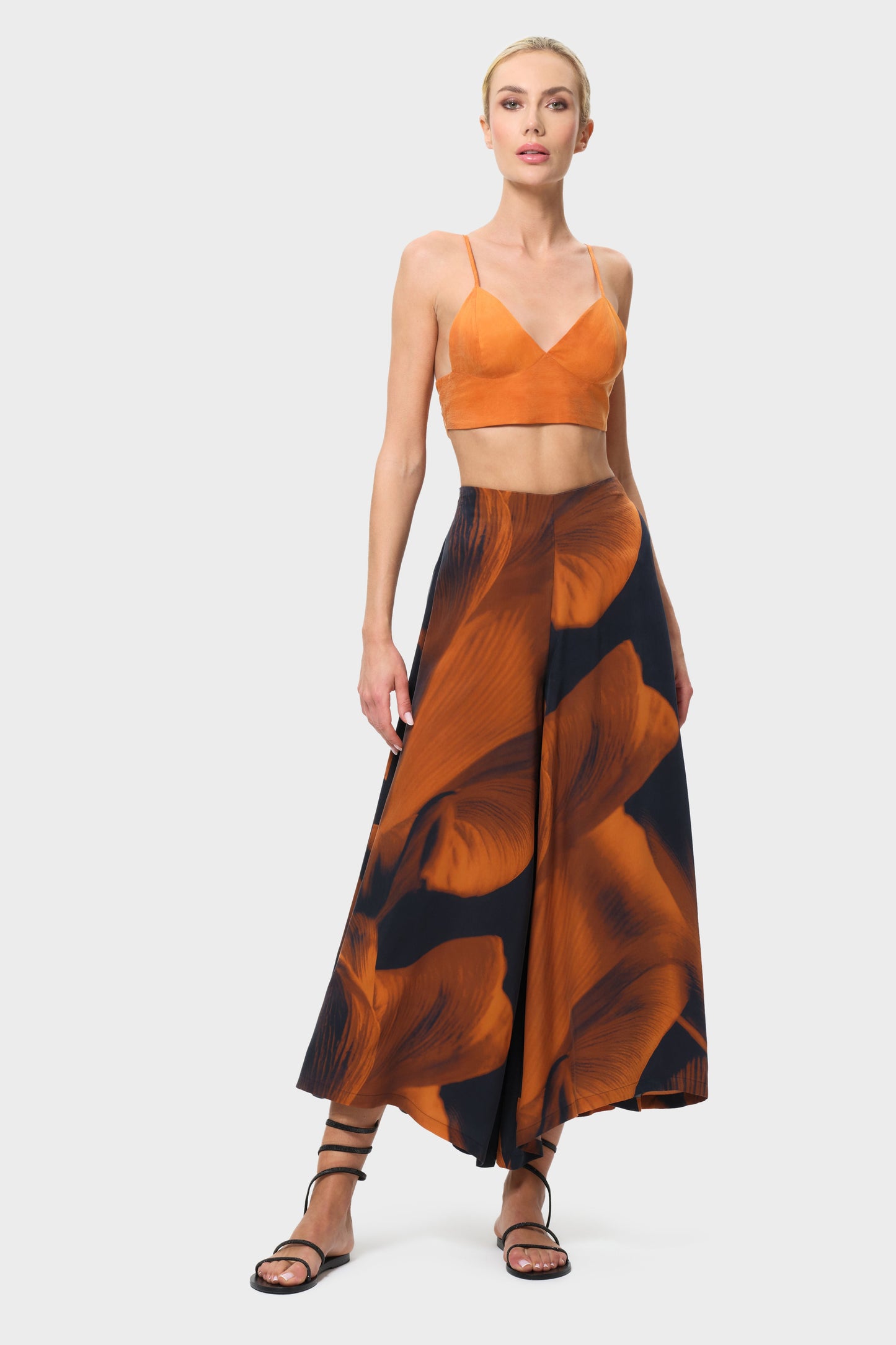 Woman wearing an orange top and patterned skirt on a white background