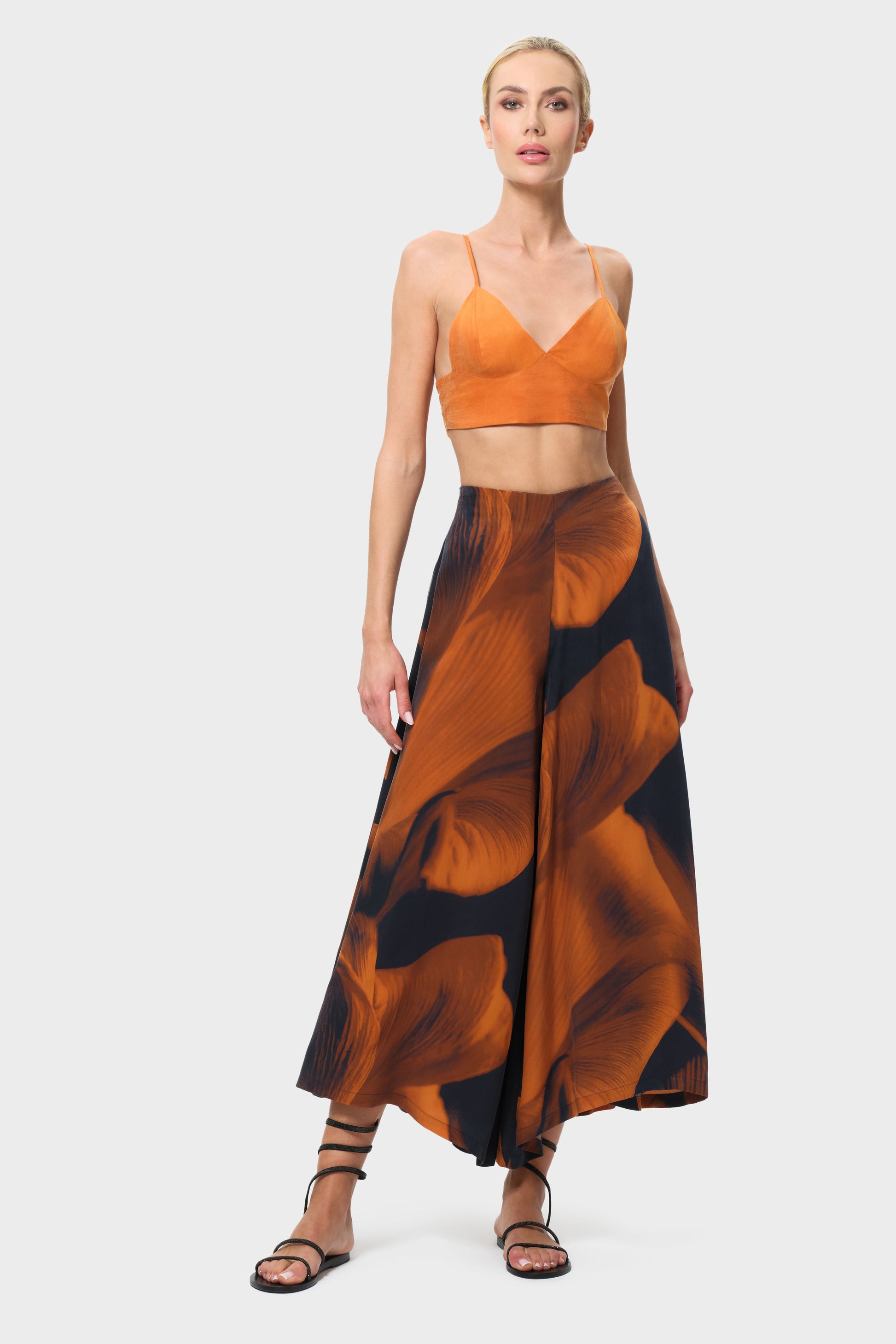 Woman wearing an orange top and patterned skirt on a white background