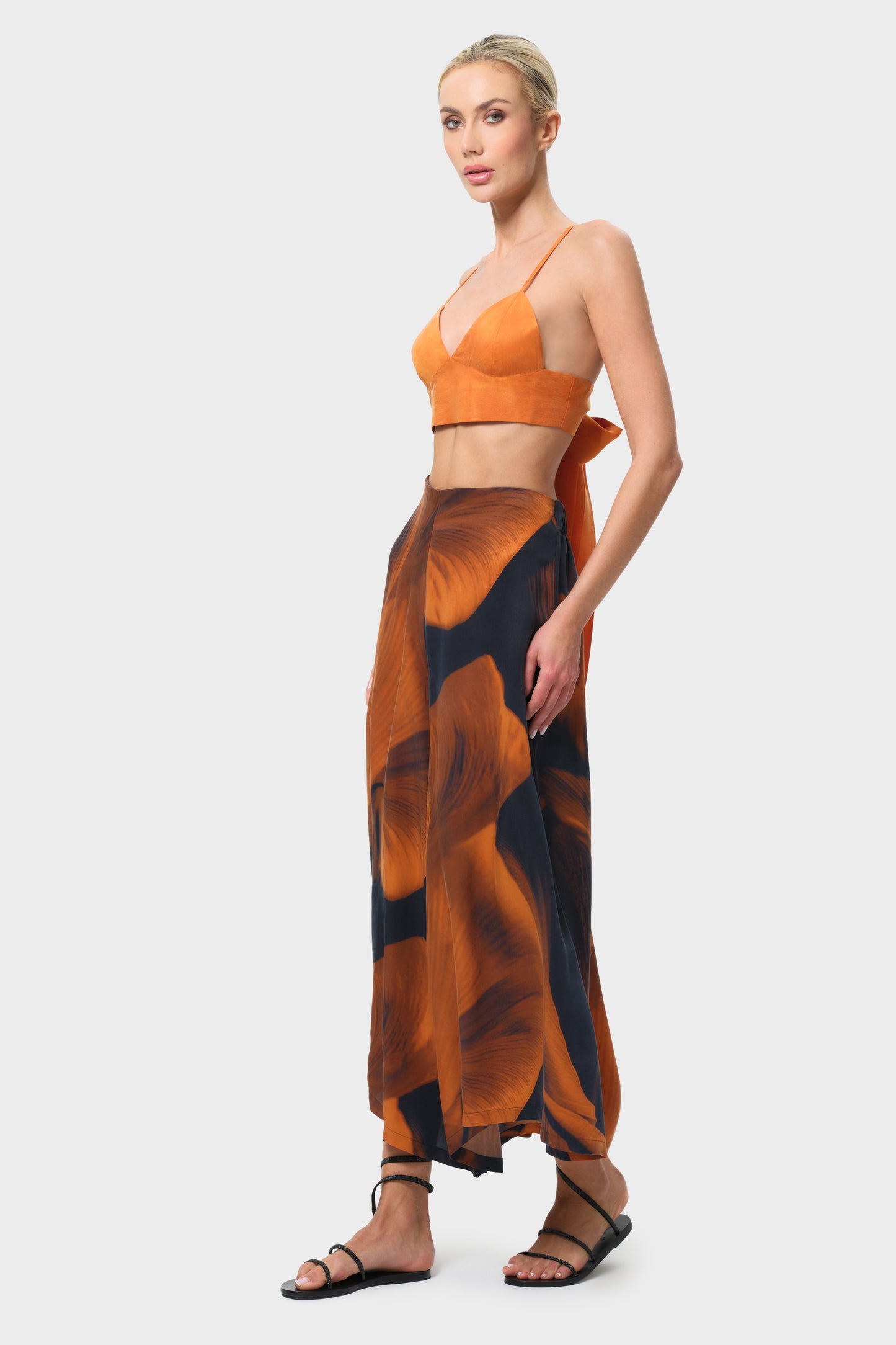 Woman wearing an orange top and patterned skirt on a white background