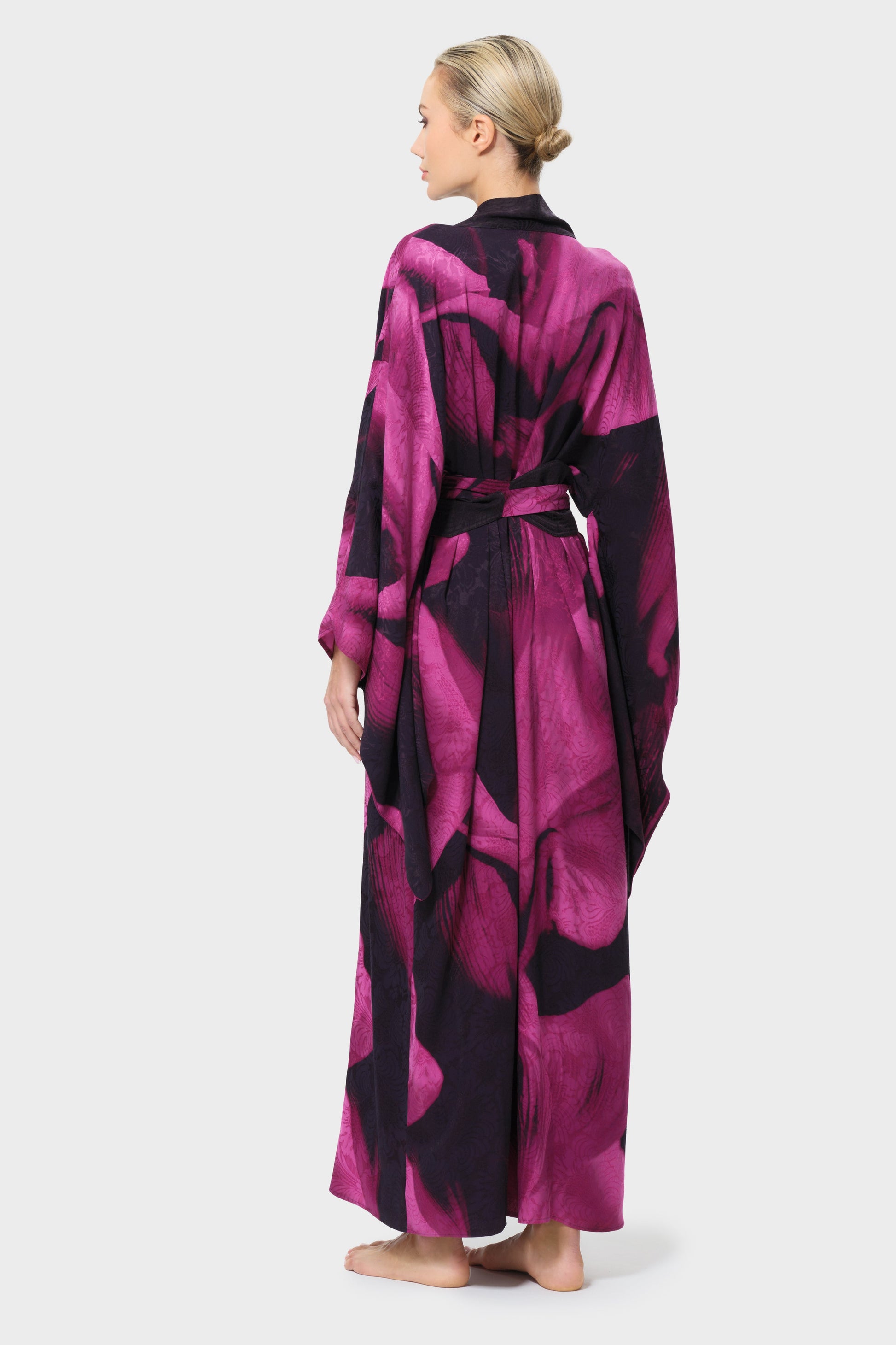 Woman wearing a pink and black patterned robe on a white background